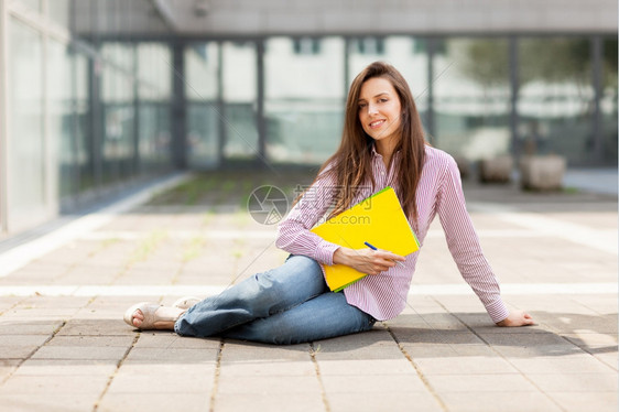 手拿着笔记本半躺在地上的女学生图片