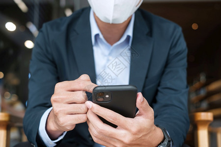 在咖啡店戴口罩使用手机的男性图片