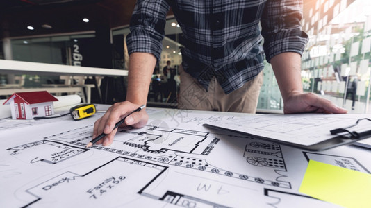 一名男建筑师测量和标志复杂蓝图大小比例的男建筑师桌子造草图图片