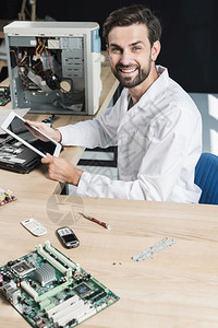 医疗的手持数码平板电脑的年轻男技师微笑着容的肖像作坊男人图片