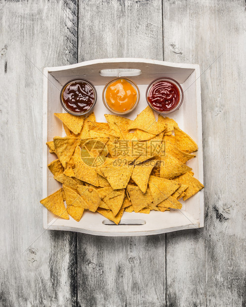 素食主义者木制的白盘中墨西哥薯片上面有三种不同的酱汁在灰色生锈木背景的顶层视野下红色的图片