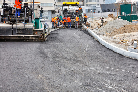 道路团队正在与两个工业摊铺机合作将第一层热沥青铺在新的一段道路上复制空间两个工业摊铺机将第一层热沥青铺在新的一段道路上劳工碎石铺图片