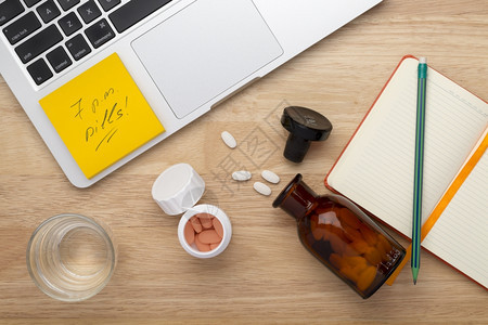 笔记本电脑在线治疗抗应激反概念桌上摆有瓶药丸的子片在线治疗概念木制桌子上摆有瓶药片痛止图片