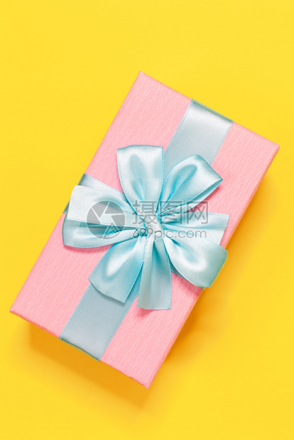 博客包裹莫斯科粉红礼物盒上面绑着蓝丝带顶在黄底的弓上垂直最小平面地观生日新年母亲节妇女庆祝活动概念图片