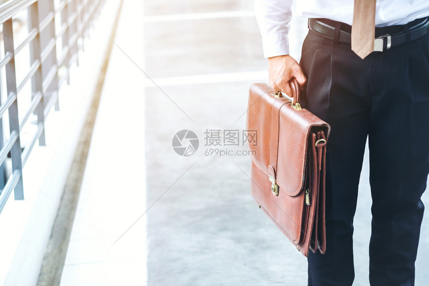 目的地白种人行政员拿着公文包的商人在户外散步的旅客图片