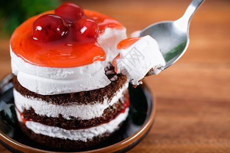 糖可口巧克力蛋糕草莓樱桃和白奶油在木制桌子上缝合盘图片