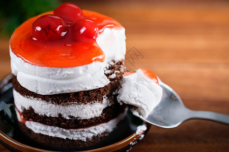 卡路里银棕色的巧克力蛋糕草莓樱桃和白奶油在木制桌子上缝合图片