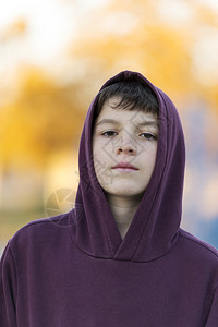 在户外的红色头罩里一个年轻有魅力的男孩肖像年轻严肃冷静图片