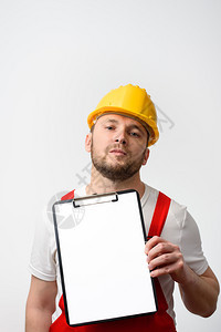 舍纳塔根工业的持有空白剪贴板Wih皮书的建筑工人关于白背景工人的色作关于白背景的空剪贴板微笑图片