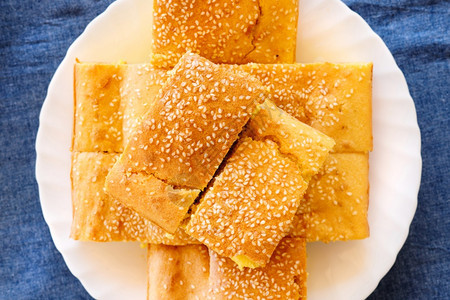 玉米面包松饼的顶端视图在桌边一张白盘子上面满是芝麻种子有机素食品烘烤的白色金子图片