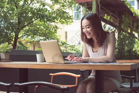 亚洲人休息舒适一位亚洲美丽的女正在使用笔记本电脑来规划工作和在家图片