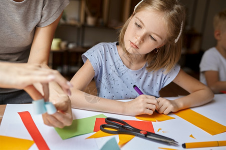 作坊学习艺术家小姑娘在桌边用彩色纸做工作小男孩在艺学校上创造课年轻画家愉快的爱好乐童年小女孩在讲习班上用彩色纸做工作图片