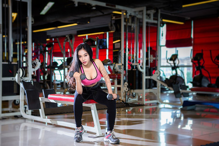 燃烧西班牙裔亚洲女在体育健身室内运动和俱乐部中进行有哑铃运动的锻练训并配有运动设备体操背景的健身俱乐部亚裔妇女力量图片