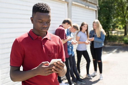 黑色的前景城市青少年男孩受到短信的欺压图片