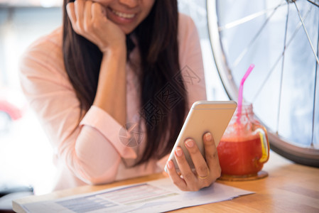 笔记本电脑股票亚洲人在咖啡店工作后使用电话手机的漂亮商业女职工在咖啡店用Iphone下班后手机图片