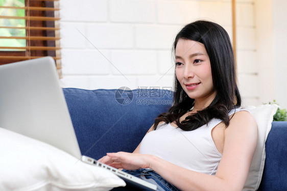 美丽的数字网络快乐亚洲女使用手提笔记本电脑微笑地躺在客厅沙发上亚洲女在家用笔记本电脑人和技术生活方式电子商业在线教育东西互联网上图片