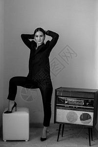 播放器身穿黑色短裤和凉鞋的美丽高加索年轻女子站在一个古老的黑白牌玩家照片旁边女商人吸引的图片