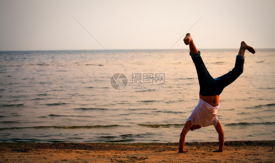 晚上霹雳舞赤脚男子在日落海滩上做手立图片