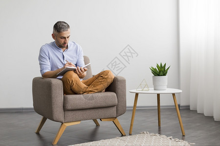 旋转正面撰写议程的男坐在椅子上人写作图片