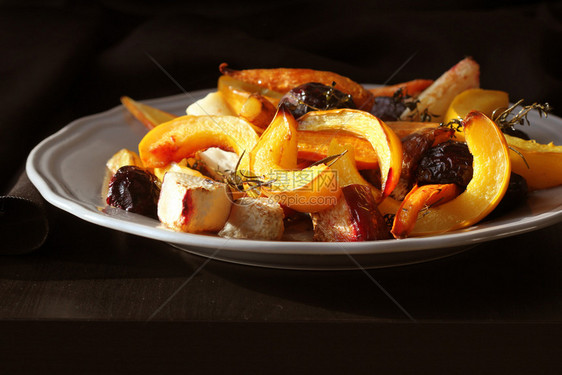 芜菁洋葱深色背景上盘子的烤秋季时令蔬菜深色背景下盘子上的烤秋季时令蔬菜从上面图片