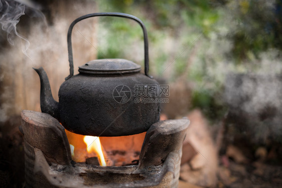 烧火时用煤炭炉灶煮旧水壶背景模糊户外烤箱目的图片