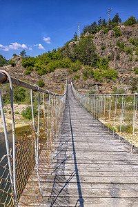 湖森林途径山上横渡河流的木绳悬吊大桥图片