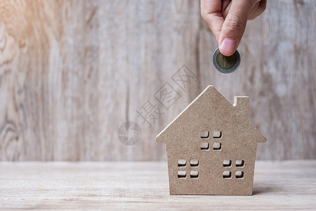 手模型财产银行房地投资成功财务和储蓄等概念在木制背景上把硬币放在房屋模型之上象征买背景