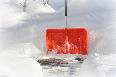 清雪概念暴风期间红色橙铲子和雪暴风后院子里用铲清洁雪冬地概念暴风雪后院子里用铲清洁冬天雪地城市服务看门人太阳维护图片