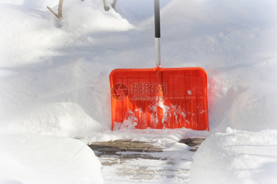 清雪概念暴风期间红色橙铲子和雪暴风后院子里用铲清洁雪冬地概念暴风雪后院子里用铲清洁冬天雪地城市服务看门人太阳维护图片