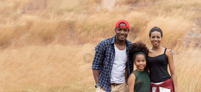 快乐的笑非洲家庭在春季夏天享受并站在草地上与黑人母亲和女儿的肖像一起在自然秋天干草田中放松了空气间笑声微相机常设图片