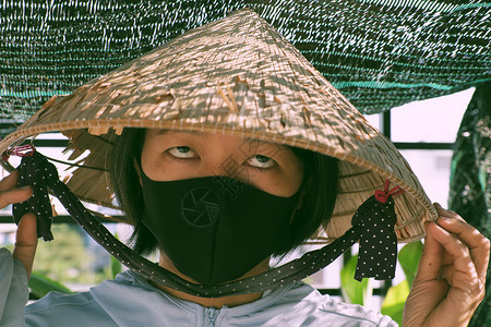 防止冠状的有趣户外概念很有趣越南妇女戴着黑色面罩和老古董帽在阳光明媚的清晨用眼瞪着睛闭上脸制造惊人的阴影和暗口罩越南语呐图片