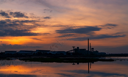 深蓝色和橙黄日落的工厂业建筑风景夜间整洁工厂周围的环境在河仓库大楼水面上反射黑蓝和橙色日落的天空城市黑暗夜晚图片