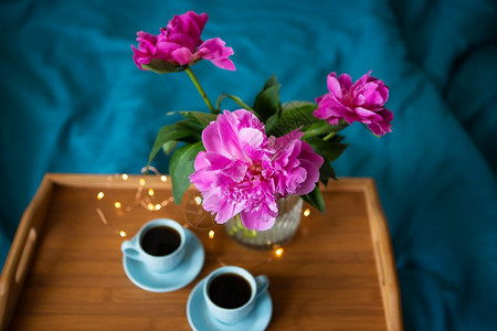 屋生日婚礼美丽的粉红小精灵和两杯咖啡正站在床上的木质托盘从美丽的粉红小豆上方近距离观察两杯咖啡站在床边的木质托盘上从面看近距离观图片