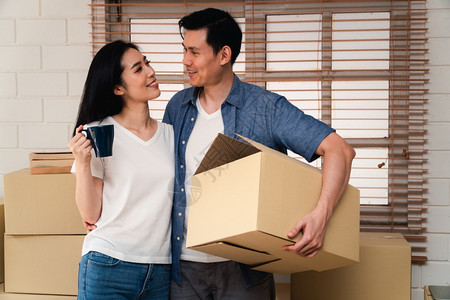 人们爱男携带纸板箱从前门走进新房子的屋内在搬家当天动迁概念租赁和房主在家搬的概念在迁出租和房主搬家的概念图片