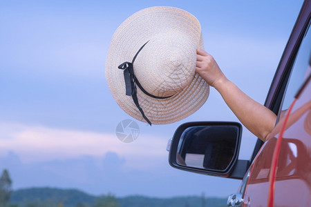 亚洲女手挥舞着宽胸帽身穿红色车窗外农村背景模糊道路旅行假期概念路边观光背景模糊车辆年轻的户外图片