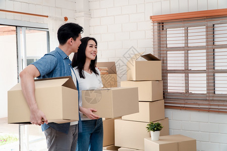 抵押成功妻子携带纸板箱从前门走进新房子的屋内在搬家当天动迁概念租赁和房主在家搬的概念在迁出租和房主搬家的概念图片