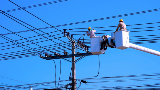 两名电动有线车上的工正努力在阳光明媚的白天用蓝晴空背景安装电线气职业极背景图片