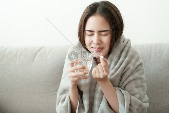 在沙发上喝水吃药的女性图片