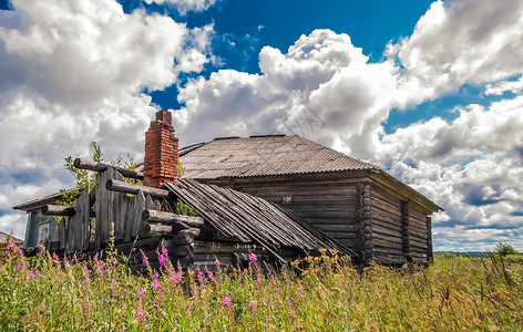 窝棚废旧木屋在一片草地的砖烟囱中用在蓝色天空下巨大的积云用烟囱砸坏的木屋场地墙图片