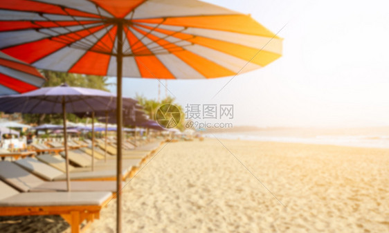 景观岛海带阳光的热沙滩上一排模糊的太阳床和多彩雨伞图片