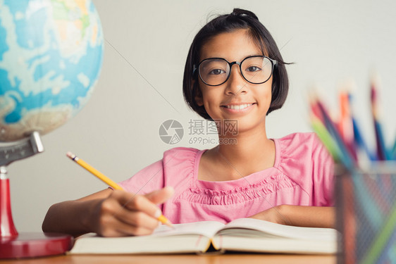 家带眼镜的亚裔女孩在课堂笔记里录着她的教育概念盒子读图片