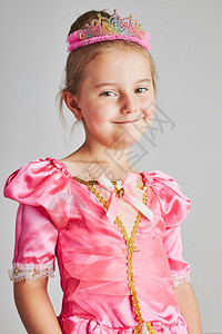 有趣的假期享受公主角色的小女孩可爱56岁女孩穿着粉色公主裙和头饰站在朴素的背景上小女孩享受她的公主角色岁女孩穿着粉色公主裙和皇冠图片