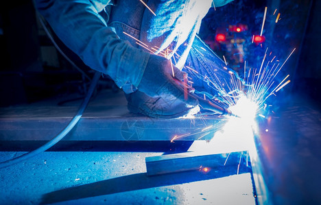 闪光焊工用氩弧机接金属并产生火花一名男子戴防护手套工业作场所的安全焊工与人在钢铁厂作修理手动的图片