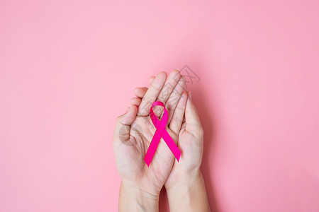 手握粉色丝带预防癌症概念图片