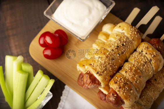 轧制面包卷紧贴的画是美味香肠零食包在松饼糕中配有芝麻种子樱桃西红柿烧菜棒和酱汁图片
