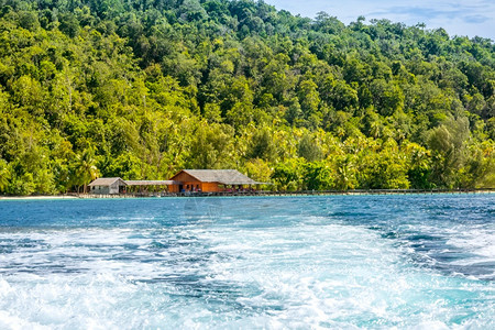 印度尼西亚Wooden码头热带岛屿在游艇水泡沫船从热带岛与Hut号起航时在游艇FaumAsster的船尾后面由岸边的水泡沫塑料铺图片