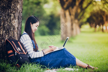 绿色时间手表微笑着美丽的亚洲女孩阅读书夏天在公园的树上工作放松一下图片