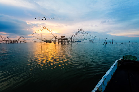 乡村的日出时天清晨空的美丽自然景观金色光亮鸟群飞翔当地渔具和稻草在泰国Pakpra运河BaanPakPraPhatthalung图片