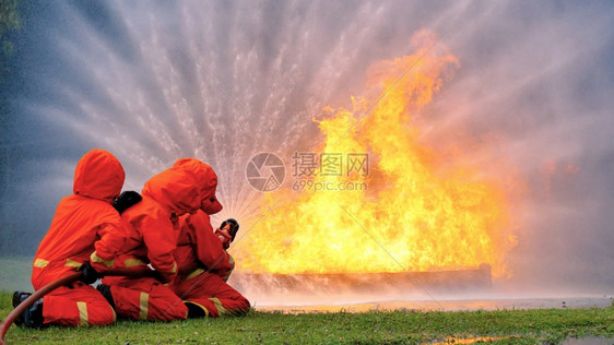 面具救援消防员用水管化学泡沫喷洒剂发动机与火焰战斗的消防员Fierman戴硬帽身穿防火灭器方面的营救训练制服工作图片
