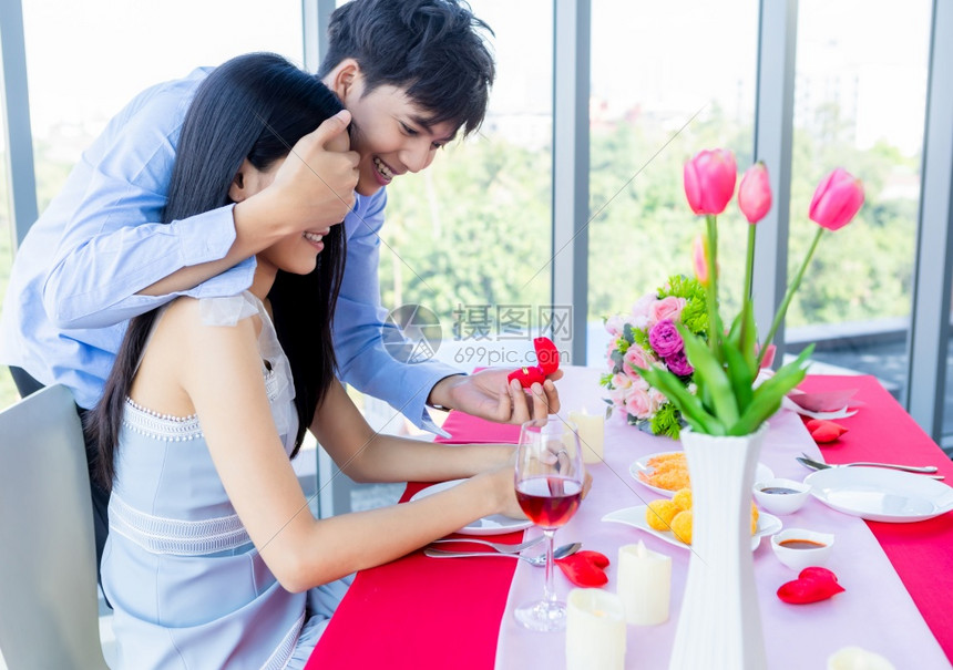 制造婚姻情人节和亚裔年轻快乐的情侣概念以订婚戒指的男人为例午餐后向女求婚在餐馆背景新娘和郎婚礼计划中在新郎和娘结婚计划中庆典图片